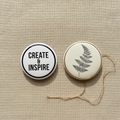 Two large 52mm customisable button badges on beige background